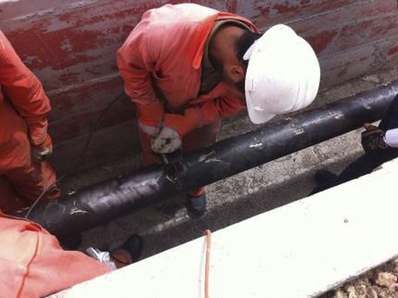 Trabajadores sobre un ducto descubierto en una trinchera